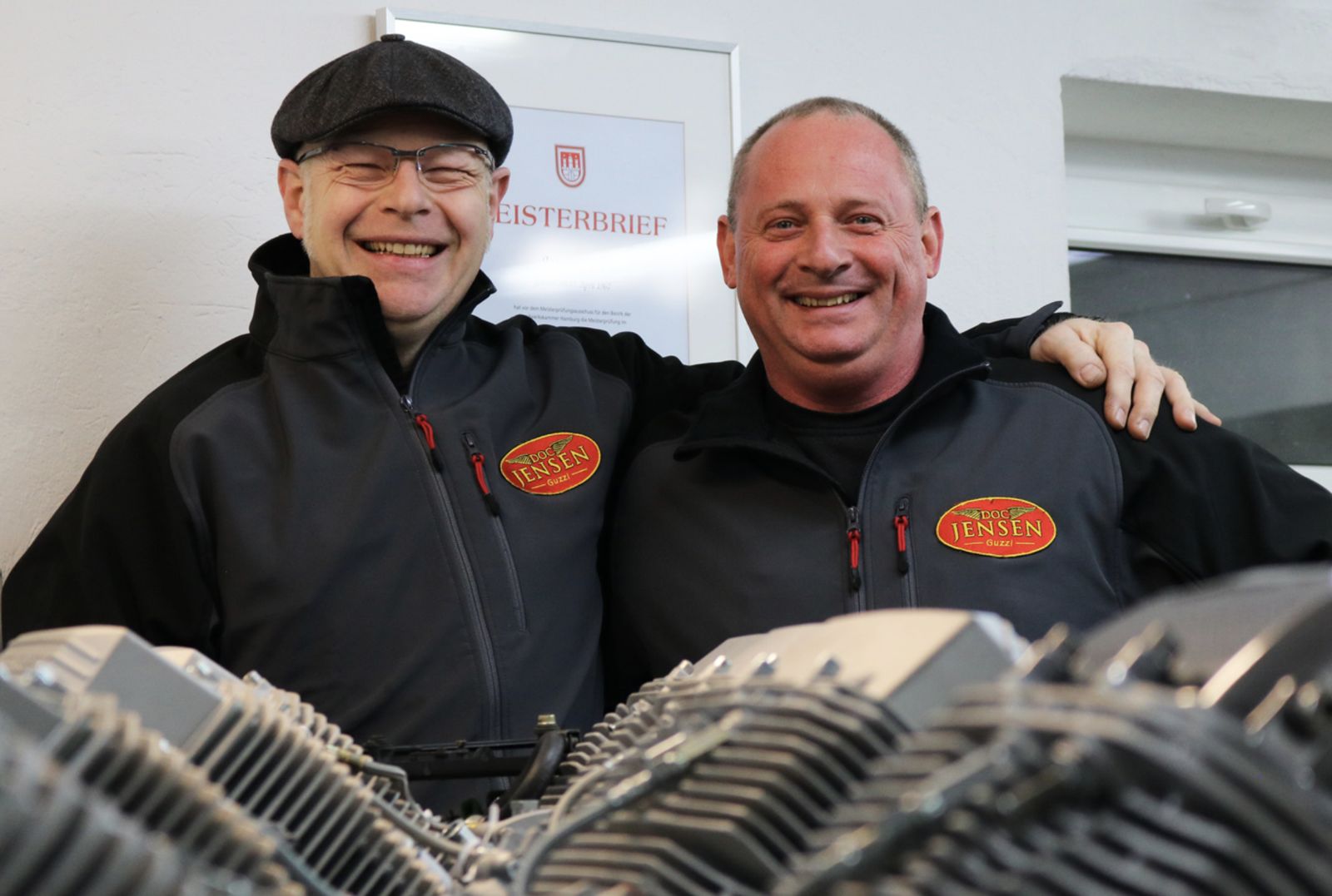 Das Team von Doc Jensen Motorrad in der Werkstatt in Schwarzenbek, vor einem Guzzi-V-Twin